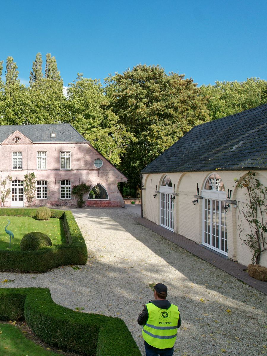 Pilote MaximumSky Photography en mission, vue de dos dans la cour d'un château en Wallonie